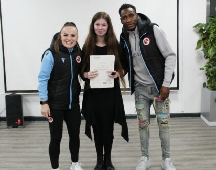 Reading Football Club players Lily Woodham and Baba Rahman standing with Lara Harman who received a certificate for completing her LASER award