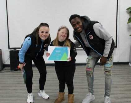 Reading Football Club players Lily Woodham and Baba Rahman standing with Rose Campbell who received an attendance certificate