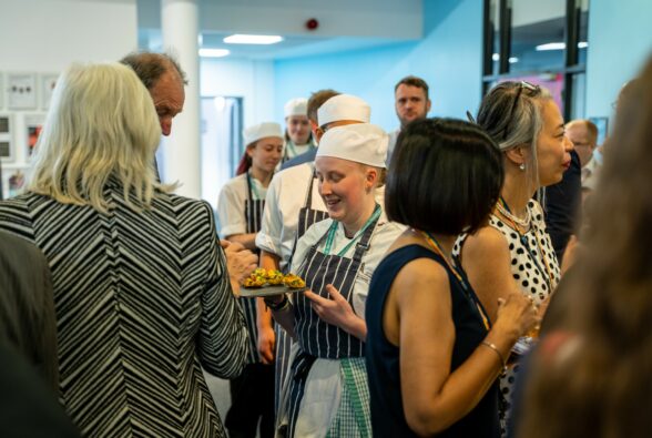 A Professional Cookery student serving canapés to a crowd