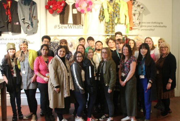 Group photo of Reading College students and staff and staff from MERL who were all involved in the project with the garments on display behind them