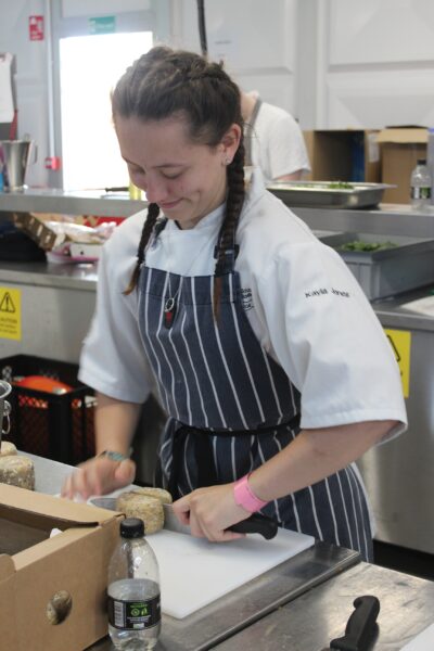 Kayla Jones, a Professional Culinary Arts Level 3 student at Reading College cutting some cheese while on work experience at Royal Ascot