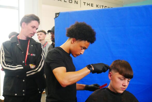 One of the judges, professional barber Sid Da Barber observes Barbering Level 2 student, Tyron Oyebade creating his winning haircut