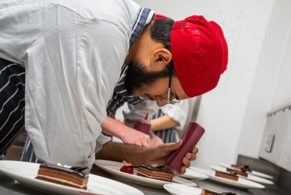 Professional Culinary Arts student Ehsan Mahmood garnishing the Chocolate layered cake dessert at the Hilton Reading for the Pride of Reading Awards.
