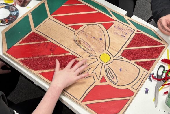 Picture of the Christmas present-themed wooden board created by three students studying a Foundation Creative Crafts Pathway at Reading College and University Centre.  