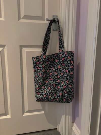 Black floral tote bag hanging on a door