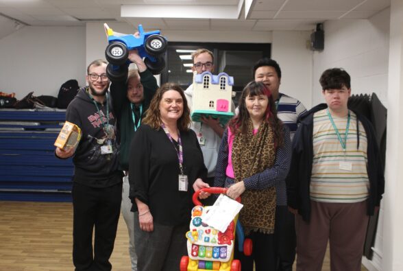 Five students and two members of staff holding toys