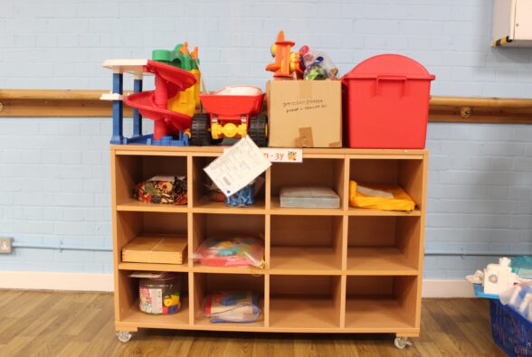 Toys in a wooden mobile shelving unit